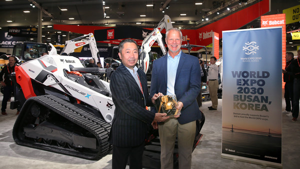 박정원 두산그룹 회장(왼쪽)이 미국 라스베이거스에서 열린 ‘콘엑스포 2023’의 두산밥캣 부스에서 마이크 볼웨버 북미 지역장에게 순금으로 만든 '두산일두(斗山一斗)'를 전달하고 있다. [두산그룹 제공]